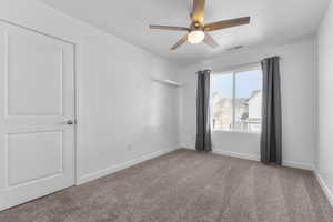 Unfurnished room featuring a textured ceiling, carpet flooring, a ceiling fan, visible vents, and baseboards