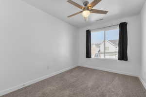 Unfurnished room with carpet floors, baseboards, visible vents, and a ceiling fan