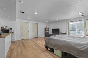 Bedroom featuring light wood finished floors, baseboards, a textured ceiling, and recessed lighting