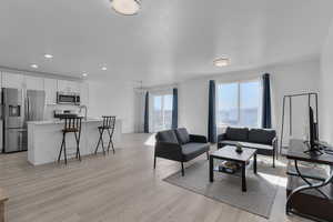 Living area featuring a textured ceiling, light wood finished floors, recessed lighting, and a notable chandelier