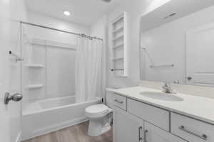 Bathroom with visible vents, toilet, wood finished floors, shower / bathtub combination with curtain, and vanity