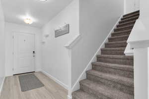 Foyer featuring light wood-type flooring, stairway, and baseboards