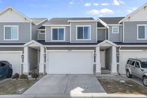 Multi unit property featuring a garage, roof with shingles, and driveway