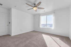 Carpeted spare room featuring baseboards, visible vents, ceiling fan, and a textured ceiling