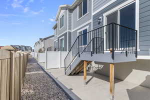 View of side of home with stairway, a residential view, fence, and a patio