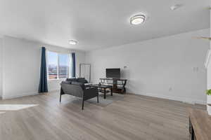 Living room featuring a textured ceiling, light wood-type flooring, and baseboards