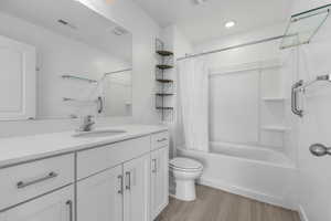 Bathroom with shower / tub combo with curtain, visible vents, toilet, vanity, and wood finished floors