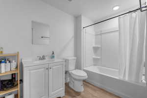 Full bathroom with shower / bath combination with curtain, vanity, toilet, and wood finished floors