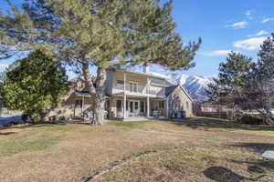 Back of house featuring brick siding, a yard, and a balcony