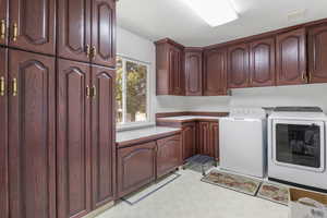 Laundry area with visible vents, a textured ceiling, washing machine and dryer, and cabinet space
