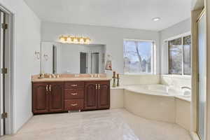 Bathroom with a garden tub, a sink, a textured ceiling, and double vanity