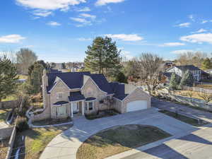 View of front of property featuring an attached garage, brick siding, fence, driveway, and a chimney