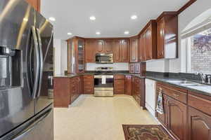 Kitchen with dark stone counters, appliances with stainless steel finishes, a sink, and recessed lighting