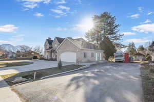 View of front of home featuring concrete driveway, brick siding, and a chimney