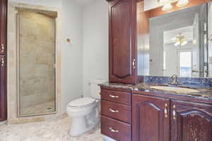 Full bath with ceiling fan, vanity, a shower stall, and toilet