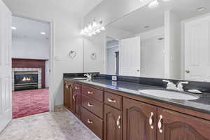 Bathroom featuring double vanity, a sink, and a glass covered fireplace