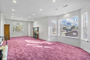 Interior space with a textured ceiling, recessed lighting, visible vents, baseboards, and a glass covered fireplace