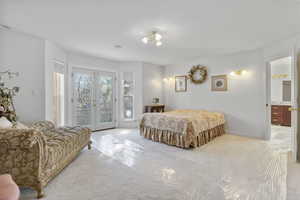 Bedroom featuring access to outside, french doors, a textured ceiling, and ensuite bath