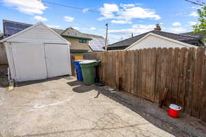 View of patio / terrace featuring fence, an outdoor structure, and a storage unit