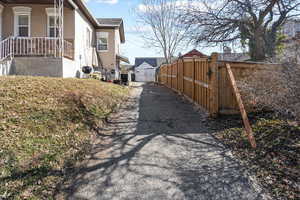 View of home's exterior featuring a gate, brick siding, fence, and covered porch