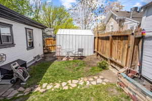 View of yard with a fenced backyard, a storage unit, and an outbuilding