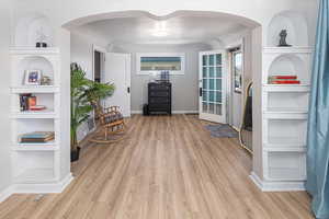 Living area featuring built in shelves, baseboards, arched walkways, and wood finished floors