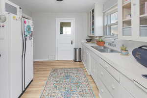 Kitchen with light wood finished floors, a sink, visible vents, and white cabinets