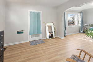 Entryway with light wood-type flooring, baseboards, and arched walkways