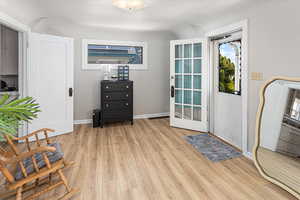 Doorway to outside with light wood-type flooring and baseboards