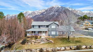 View of front of house with covered porch, a chimney, a mountain view, and a front yard