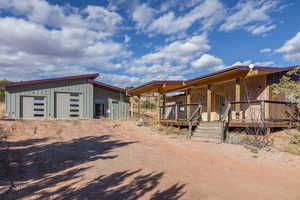 View of front of home featuring board and batten siding, an outbuilding, a detached garage, and dirt driveway