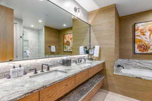 Bathroom with double vanity, tile patterned flooring, a sink, and a bath