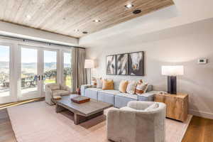 Living room featuring wood ceiling, light wood-style flooring, a tray ceiling, a mountain view, and recessed lighting