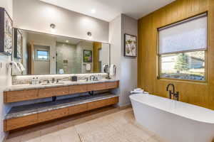 Full bath with double vanity, a stall shower, a freestanding bath, and a sink