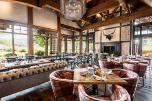 Dining room with high vaulted ceiling, beamed ceiling, wood-type flooring, and a fireplace