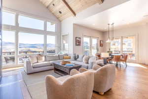 Living area with high vaulted ceiling, wooden ceiling, a mountain view, wood finished floors, and beam ceiling