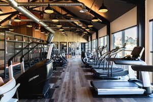 Exercise room with high vaulted ceiling and wood finished floors