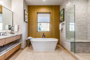 Bathroom featuring wooden walls, vanity, a soaking tub, a shower stall, and tile patterned floors