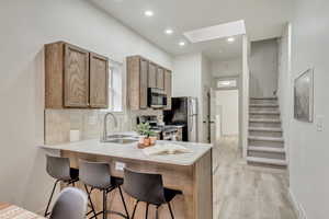 Kitchen featuring stainless steel appliances, a breakfast bar area, a skylight, and a sink