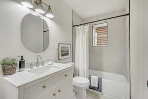 Full bathroom featuring toilet, shower / bathtub combination with curtain, and vanity