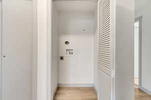 Laundry area with hookup for a washing machine, light wood-style floors, electric dryer hookup, laundry area, and baseboards