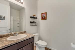 Full bath featuring toilet, curtained shower, baseboards, and vanity