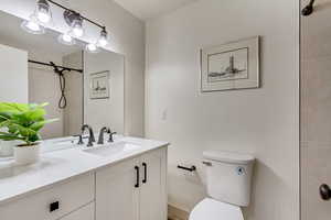 Bathroom featuring toilet, tiled shower, and vanity