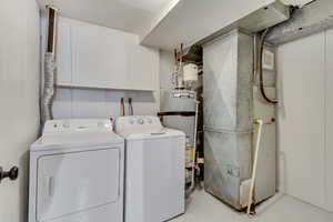 Laundry area featuring heating unit, water heater, and washing machine and clothes dryer