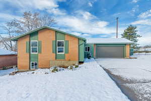 View of front of home with a garage, brick siding, and driveway