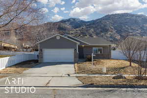 Single story home with an attached garage, a mountain view, brick siding, fence, and concrete driveway