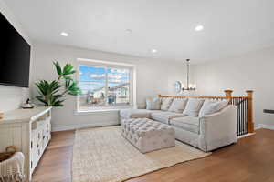 Living room with a chandelier, baseboards, light wood-style flooring, and recessed lighting