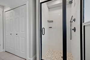 Bathroom featuring a closet, tile patterned flooring, and a shower stall