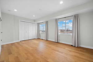 Primary bedroom with recessed lighting, light wood-style flooring, and baseboards