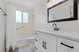 Bathroom with toilet, shower / bath combo, tile patterned flooring, and vanity